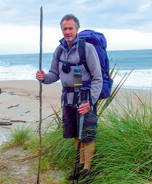 Founder of the World Transformation Movement NZ Centre, Pete Sadler standing on a beach Founder of the World Transformation Movement NZ Centre, Pete Sadler standing on a beach